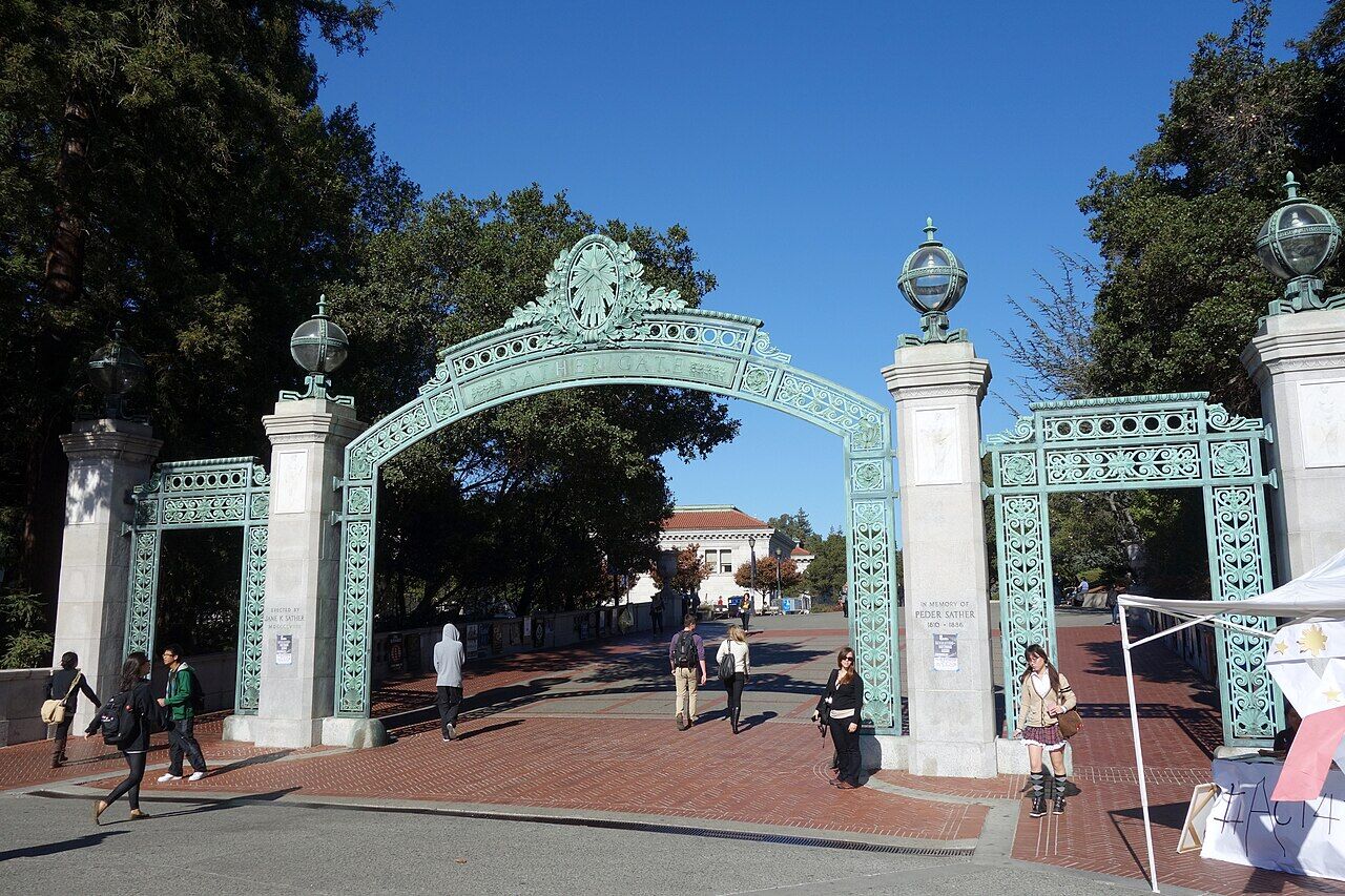 Distinctive green and white Sather Gate archway with people walking through